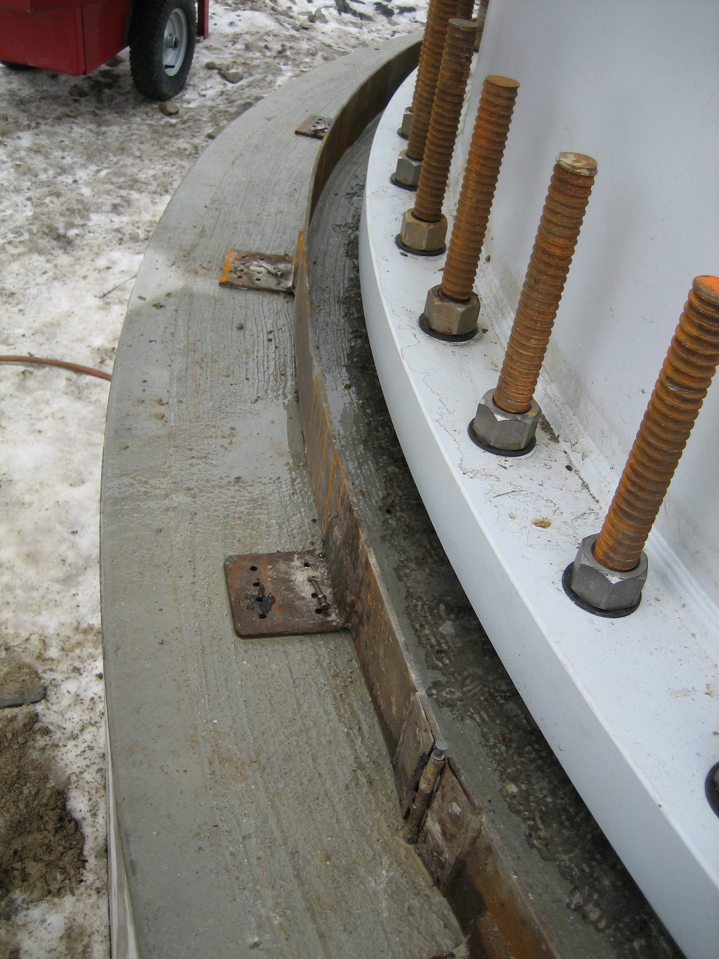Close-up of anchor bolts and levelling nuts on the embedment ring of a completed tower foundation pedestal.