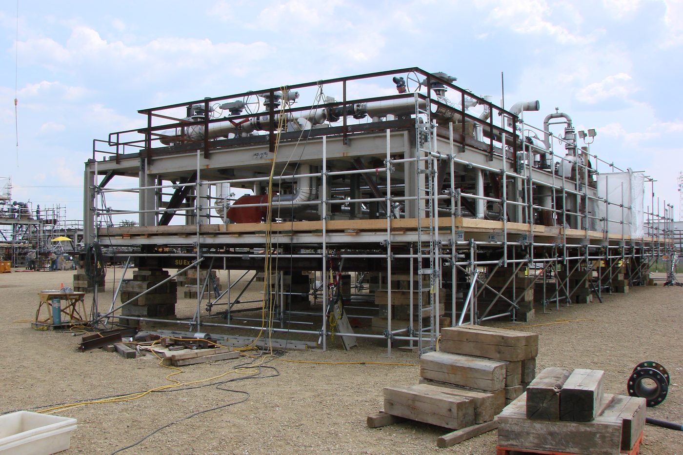 Steel-framed building modules set on temporary supports and being connected together on site.