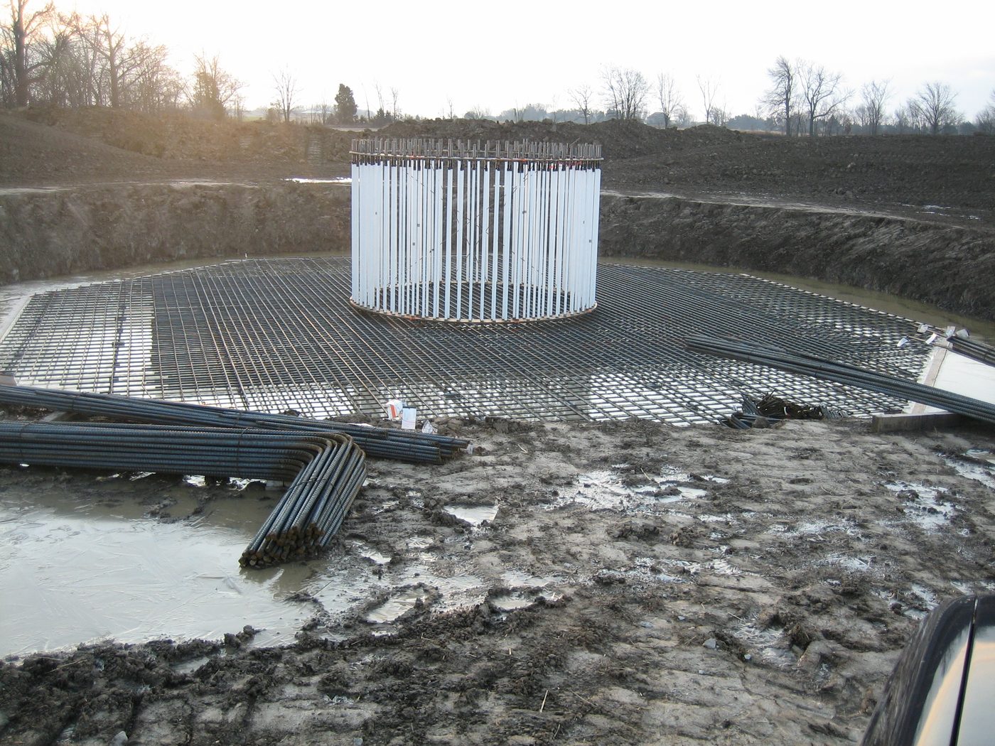 Excavated turbine foundation with the full reinforcing mat placed and the anchor cage standing at the centre.